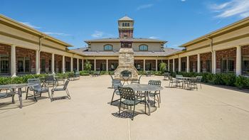 A courtyard with tables and chairs and a building in the background.